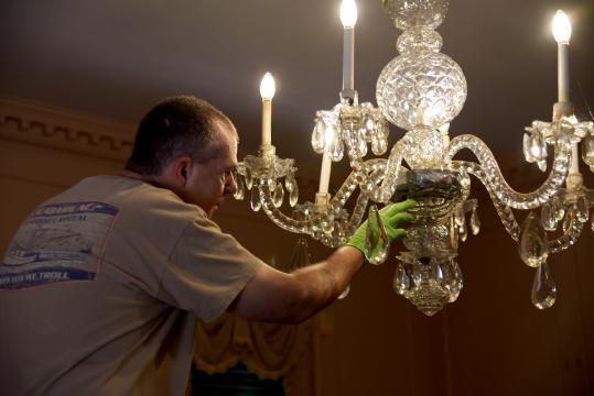 Fixing a chandelier inside the Stanly House at Tryon Palace