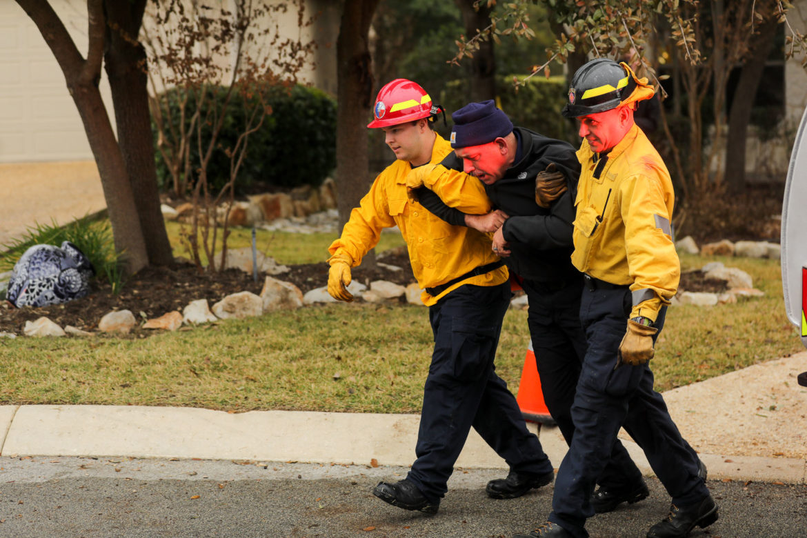 Firefighters aid a pedestrian during a simulated medical emergency involving smoke inhalation from nearby wildfires.