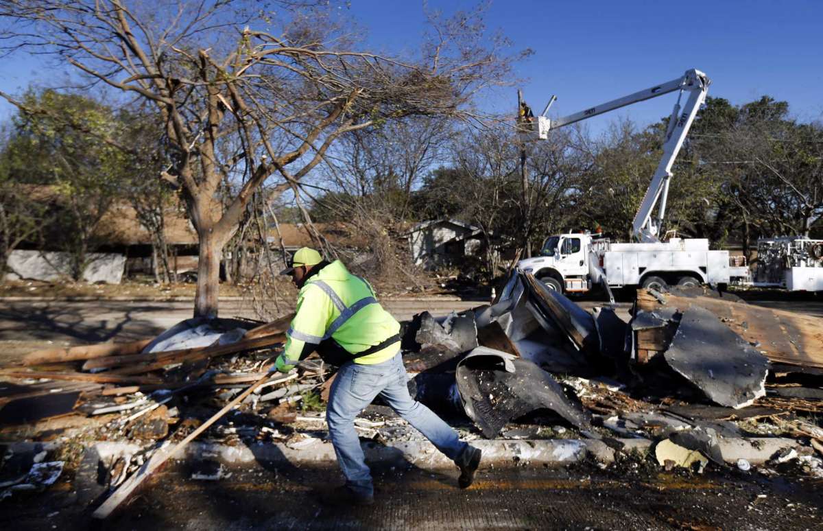 A City of Arlington street crewman cleans up debris from The Mirage Apartments complex along Pioneer Parkway in Arlington, Texas, Wednesday, Nov. 25, 2020, after a tornado-warned storm torn the roofing off. Air conditioner units and other structural debris were scattered across the property and street. The crew is trying to get the major thoroughfare open. (Tom Fox/The Dallas Morning News via AP)