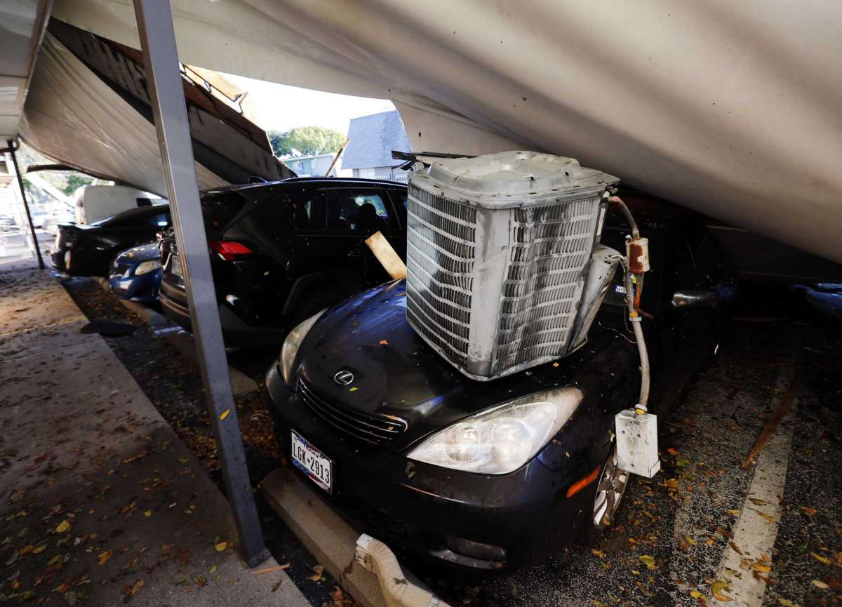 An air conditioner unit of a Waterdance Apartments building and the peeled off roof landed on a car during a tornado-warned storm that rolled through Tuesday night. Damage also occurred at The Mirage Apartments along Pioneer Parkway in Arlington, Texas Wednesday, Nov. 25, 2020. (Tom Fox/The Dallas Morning News via AP)