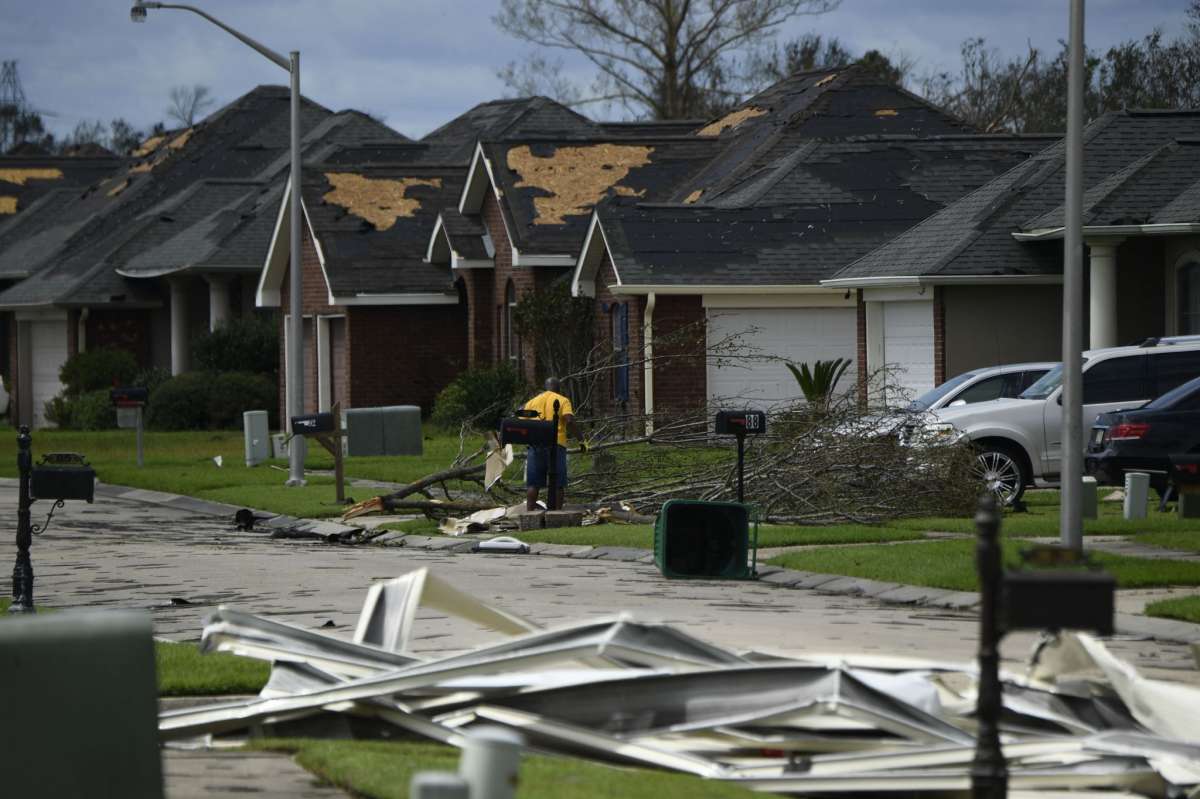 A person picks up debris damage near their home in Laplace, Louisiana, on August 30, 2021 after Hurricane Ida made landfall. - Powerful Hurricane Ida battered the southern US state of Louisiana, leaving at least one dead and knocking out power for more than a million people, including the whole of New Orleans. Ida slammed into the Louisiana coast as a Category 4 storm on August 29, 2021, 16 years to the day after Hurricane Katrina devastated New Orleans, but had weakened to a tropical storm early August 30, 2021.The storm knocked out power for all of New Orleans, with more than a million customers across Louisiana without power, according to outage tracker PowerOutage.US. (Photo by Patrick T. FALLON / AFP) (Photo by PATRICK T. FALLON/AFP via Getty Images)